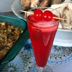 close up of American Fizz Cocktail in a vintage automotive motif glass garnish with cherries in pick