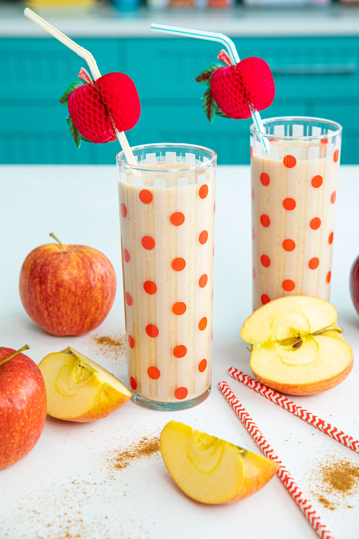 close up of apple smoothie on a counter top surrounded by apples and cinnamon