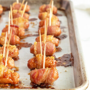 brown sugar bacon wrapped smokies lined on a baking pan