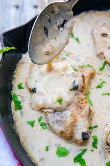 spooning mushroom soup sauce onto baked porkchops