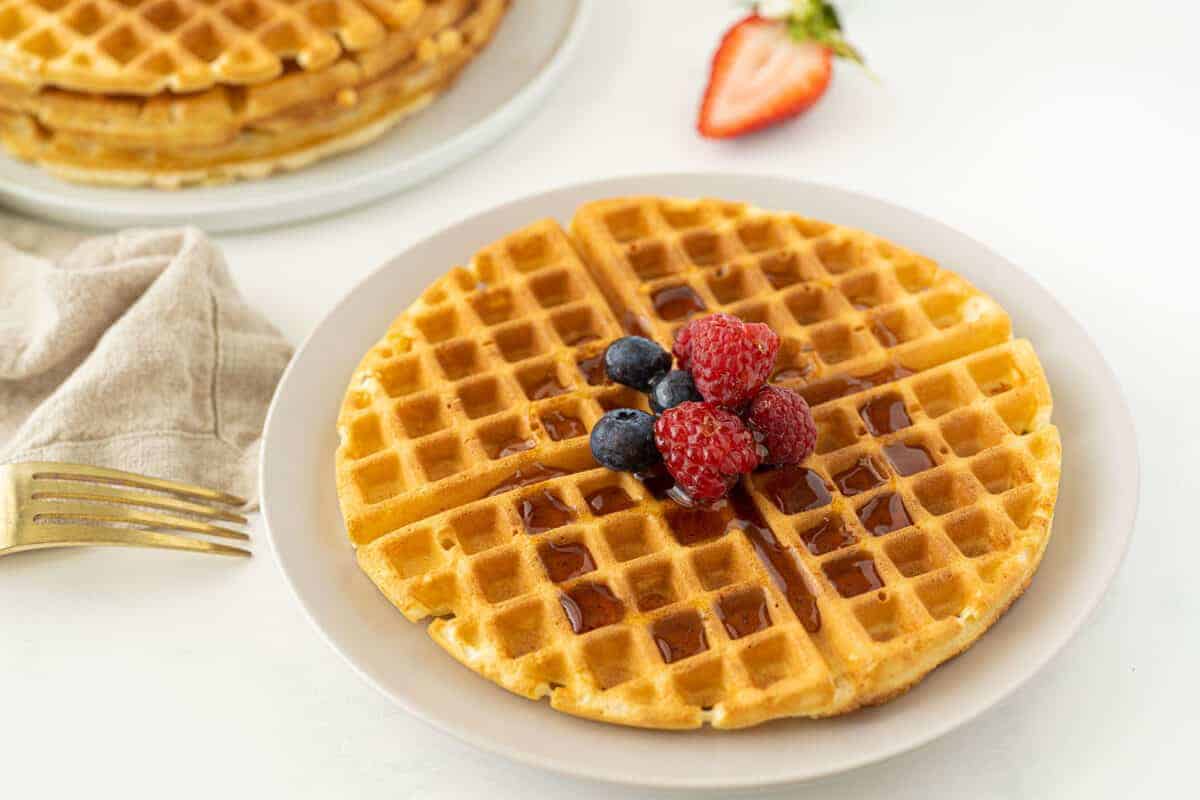 bisquick waffles on a white plate with syrup and berries