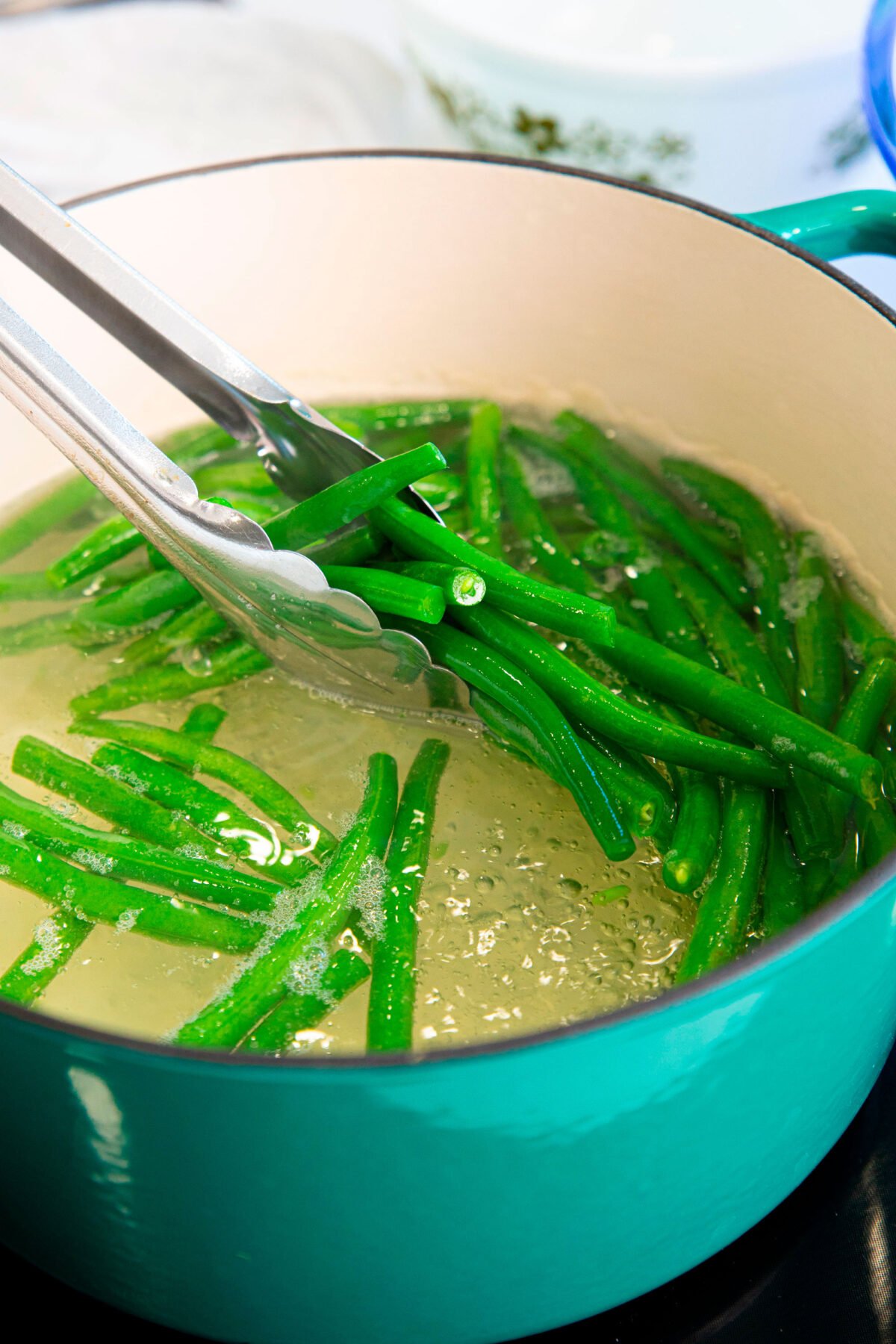 green beans in tongs in boiling water