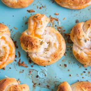 Top down shot of Cheese Stuffed Garlic Knots on jade blue background