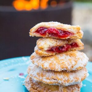 close up of Campfire Cherry Hand Pies in a blue plate with one piece broken into two showing the inside