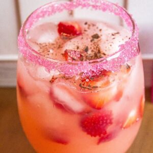 close up of Cupid's Arrow cocktail in a Glass with rim dipped in red sugar crystals