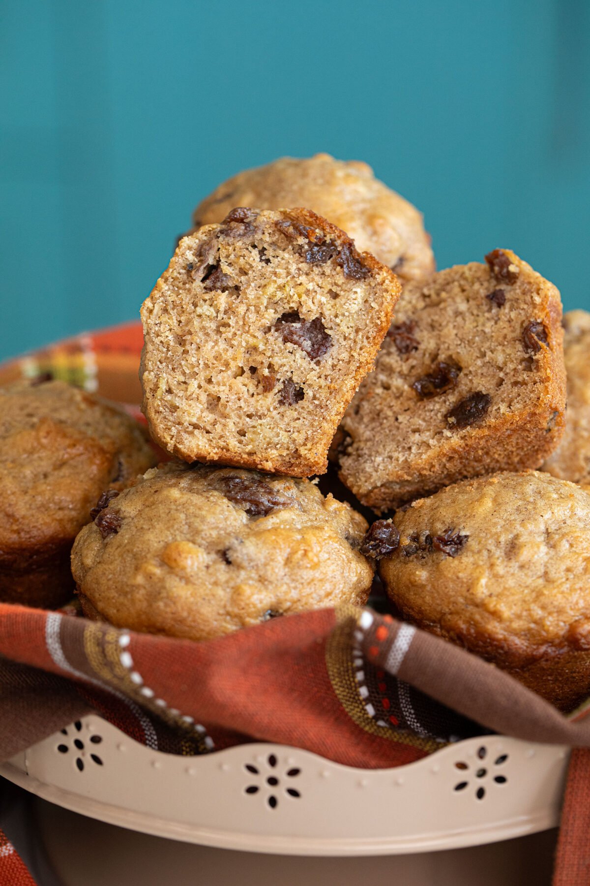 cinnamon raisin oat bran muffins on a orange cloth one cut in half