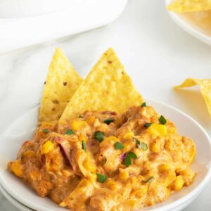 corn dip on a white plate with corn chips