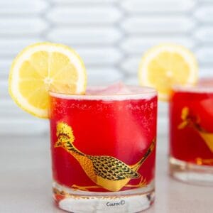 Cranberry Whiskey Sour in a vintage roadrunner decorated glass garnished with lemon