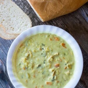 close up of Chicken & Wild Rice Soup in a bowl with a crusty loaf of French bread on side