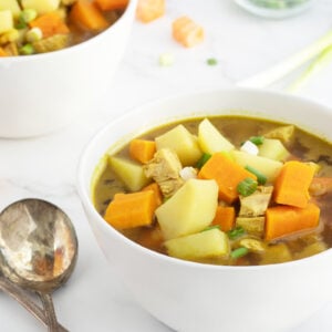 curried sweet potato and chicken soup with spoons beside bowl