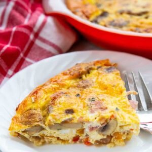 close up white plate with a slice of Ham & Mushroom Crustless Quiche and a fork