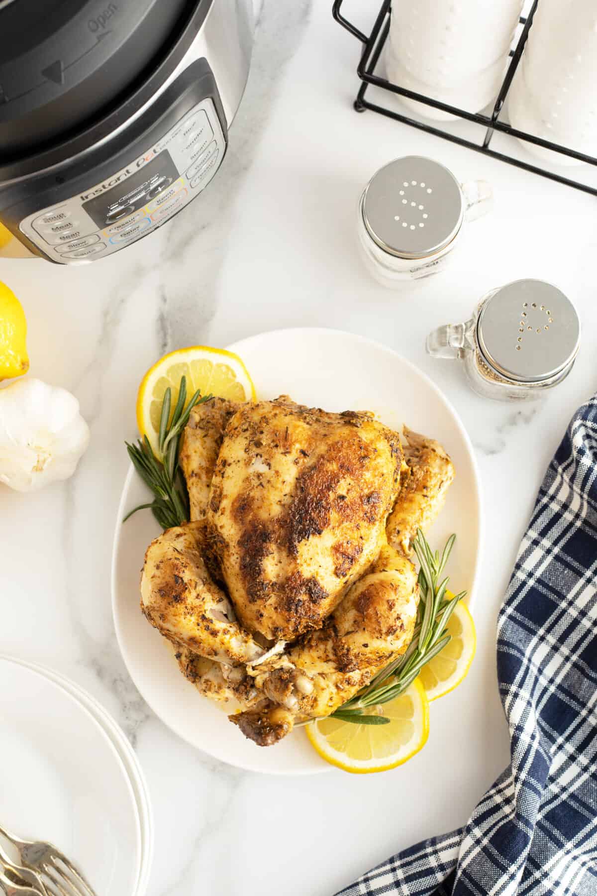 Instant Pot Whole Chicken overhead view of it on a platter with sliced lemon and herbs