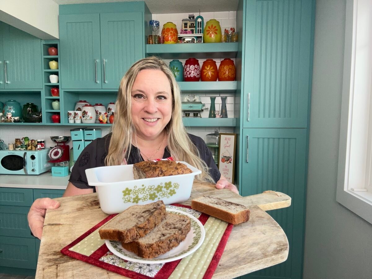 Karlynn Johnston holding a wooden board with cinnamon swirl bread on top of it in her kitchen