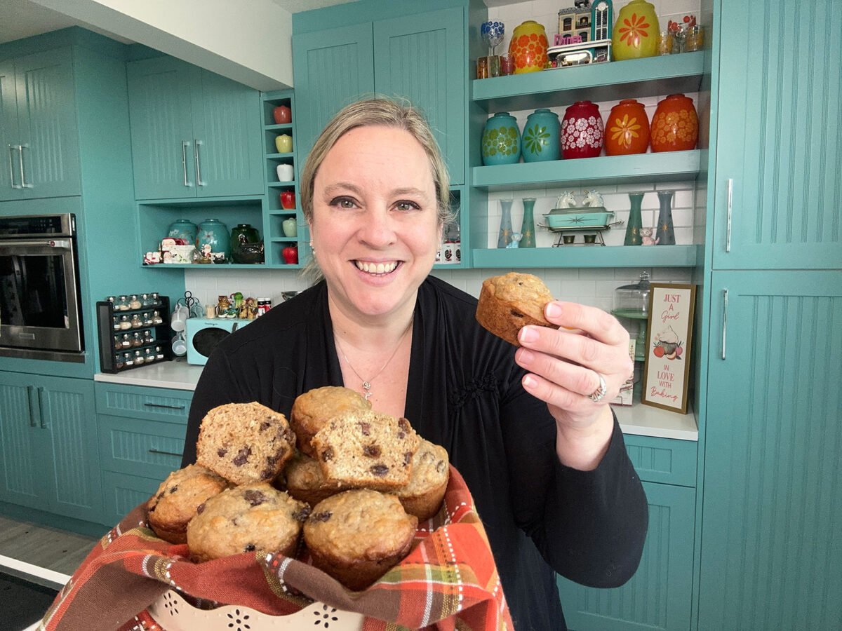 Karlynn holding up one cinnamon raisin oat bran muffins and a bowl full of them in her other hand