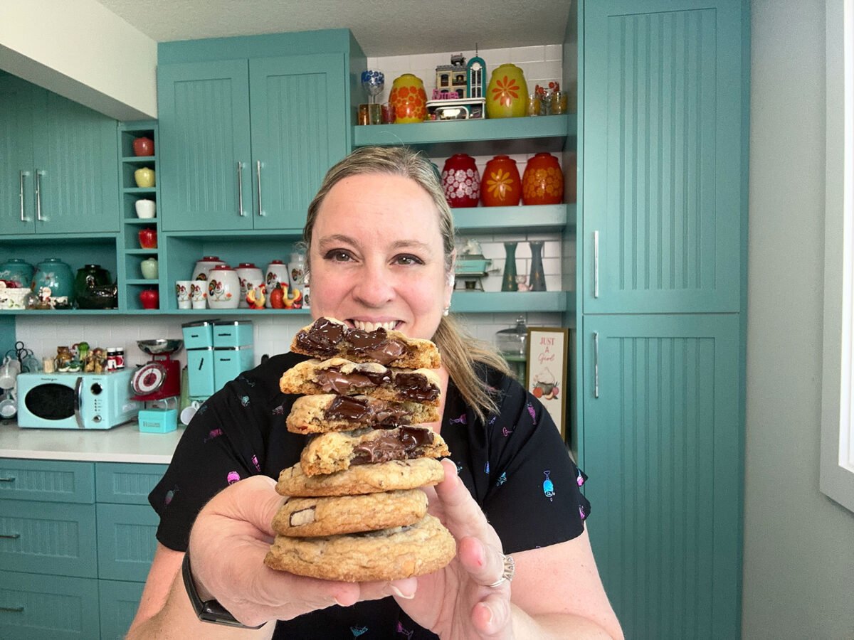 Karlynn holding up a stack of Nutella Stuffed Hazelnut Chocolate Chip Cookies showing the inside gooey centers.