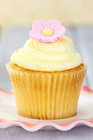 Lemon Buttercream Frosting and pink icing flower on top of lemon cupcake