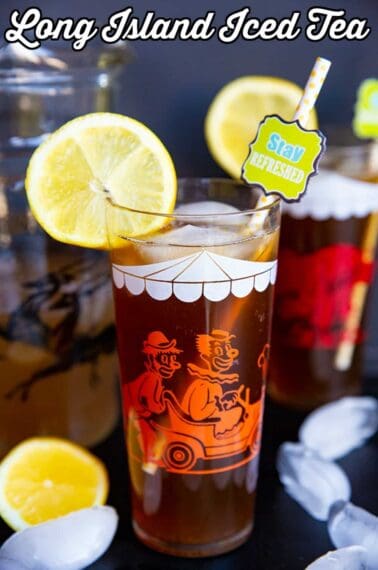 close up glass of Long Island Iced Tea garnish with slice of lemon, a pitcher and another glass on its background