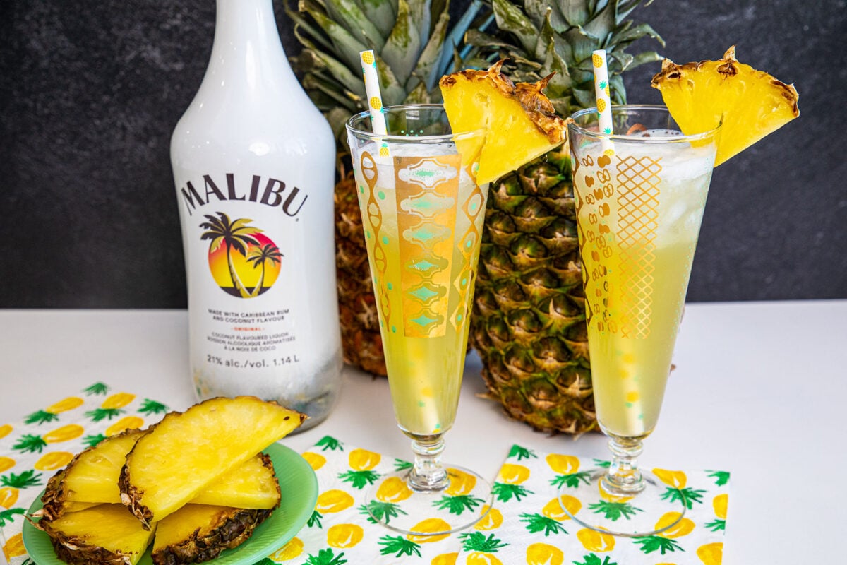 Malibu and Pineapple cocktails on a counter with pineapples in the back ground