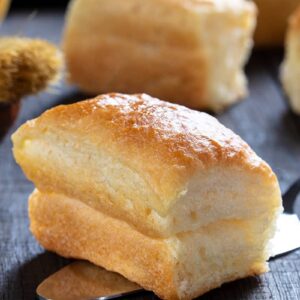 close up piece of soft buttery delicious Parker House Rolls on a wooden background