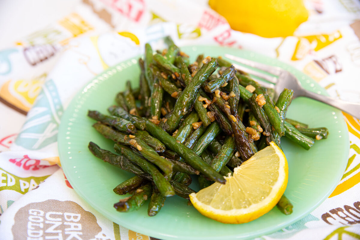 sauteed green beans on a plate  with a slice of lemon