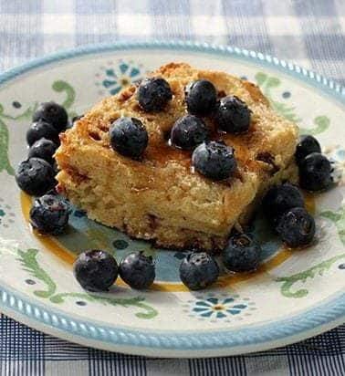 close up of Baked French Toast with maple syrup and fresh blueberries in small dessert plate