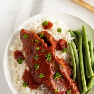 slow cooker short ribs on a plate with rice and green beans on the side