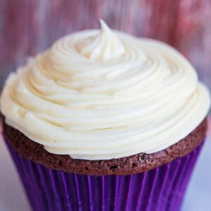 close up Cream Cheese Icing swirled on a cupcake with blue cupcake liner