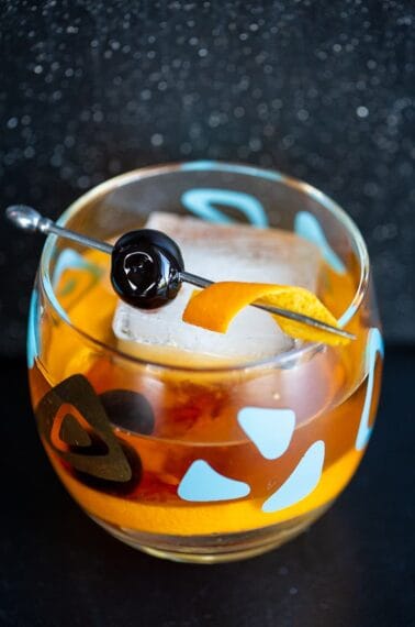 close up Old Fashioned cocktail in an old fashioned glass garnish with cherry and orange