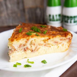 close up slice of Bisquick Quiche in a white plate, salt and pepper shakers on background