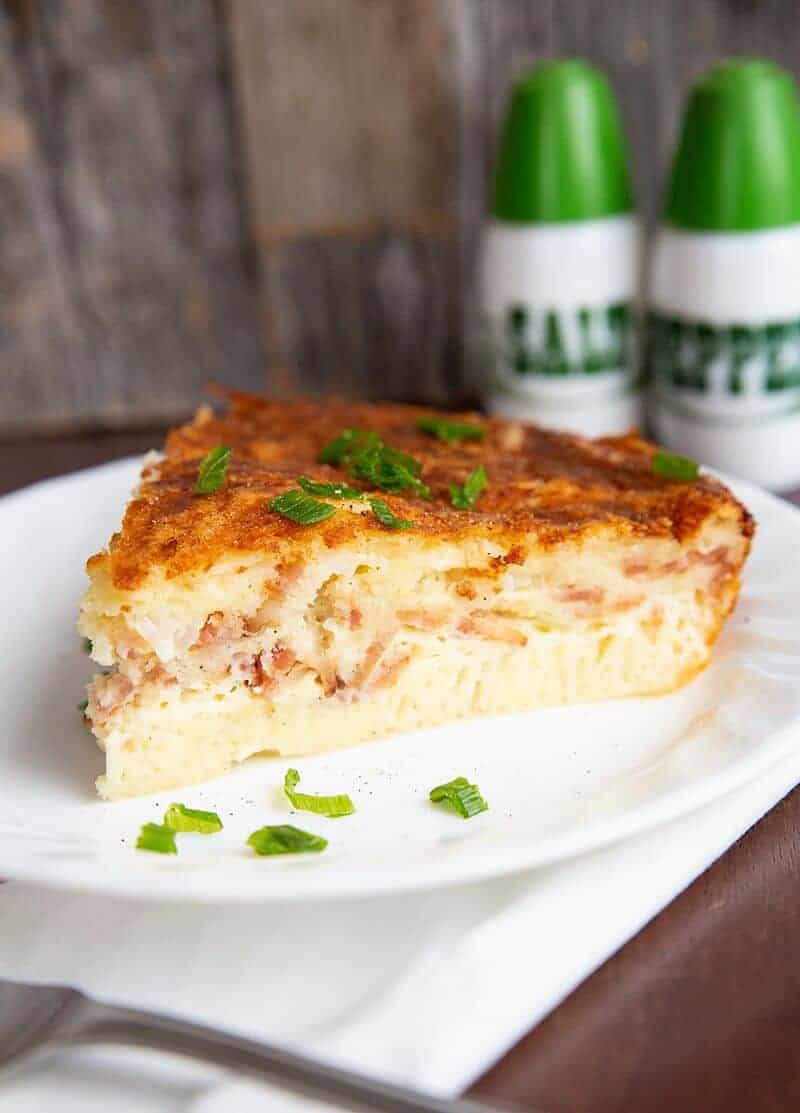 close up slice of Bisquick Quiche in a white plate, salt and pepper shakers on background