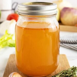 vegetable broth in a mason jar with lid on top sitting on a cutting board