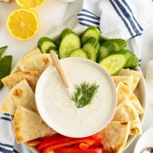 Whipped Feta Dip in a bowl on a platter with chips and sliced vegetables